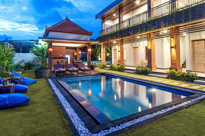 Swimming pool area surrounded by grass area and bean bags at La Sari Village Canggu, Bali