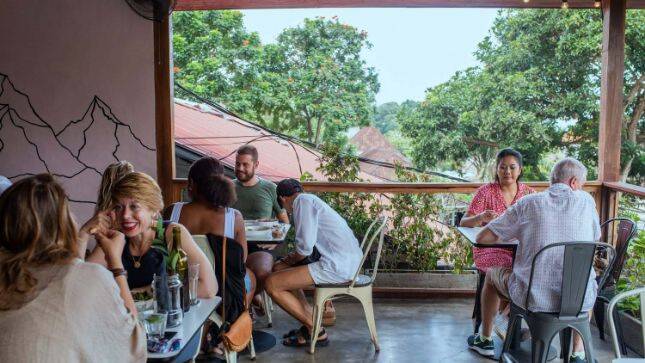 Travellers eating breakfast on outdoor balcony at Suka Espresso Ubud, Bali
