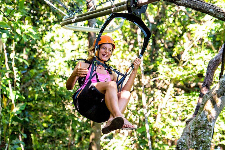 Woman ziplining through rainforest at Kula Wild Adventure Park, Fiji
