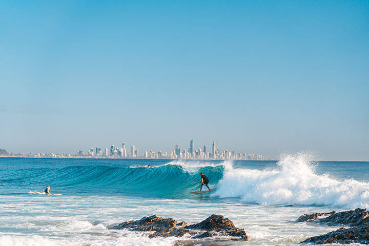 Surfing a Currumbin Beach with Surfers Paradise in background.  