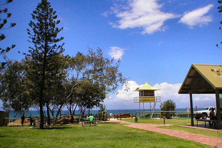 Lifeguard tower and park with picnic shelter, shady trees and benches at Nobby Beach, Gold Coast