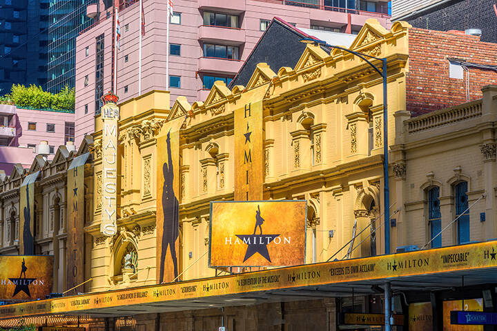 A front view of Her Majesty's Theatre in Melbourne, decorated with the signage of the musical production Hamilton