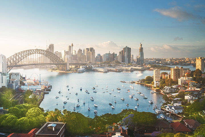 Sunrise over Sydney harbour, featuring the Sydney Harbour bridge, Sydney skyline and boats on the water. 