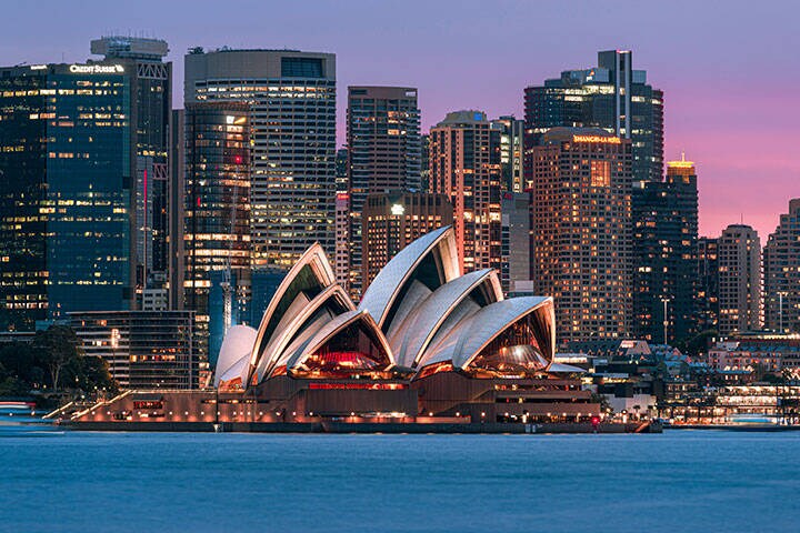 Sydney Opera House, an Australian iconic with city CBD illuminated in the sunset sky
