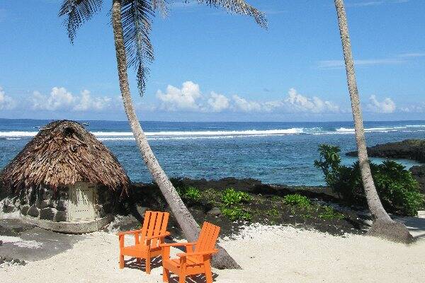 Orange chairs on white sand beach, Samoa