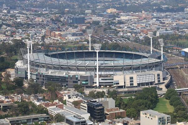  An outdoor aerial view of the Melbourne Cricket Ground (MCG) during a Boxing Day test match, showcasing the bustling crowd and players on the field.