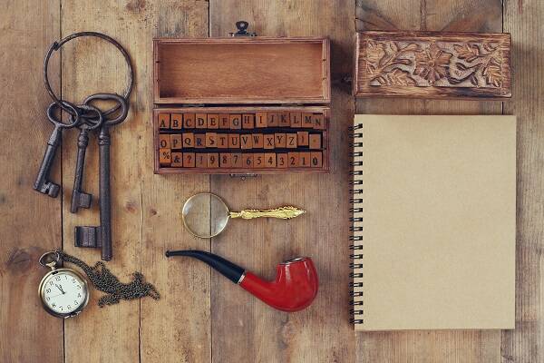 A flat lay of detective tools and clues arranged on a wooden box at an escape room in Sydney, showcasing magnifying glasses, notes, and other intriguing items.