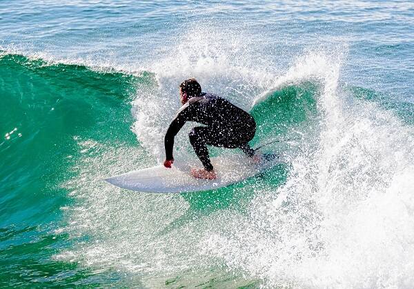 A scenic view of Bells Beach, featuring a surfer riding powerful waves in the deep sea, surrounded by frothy white foam.