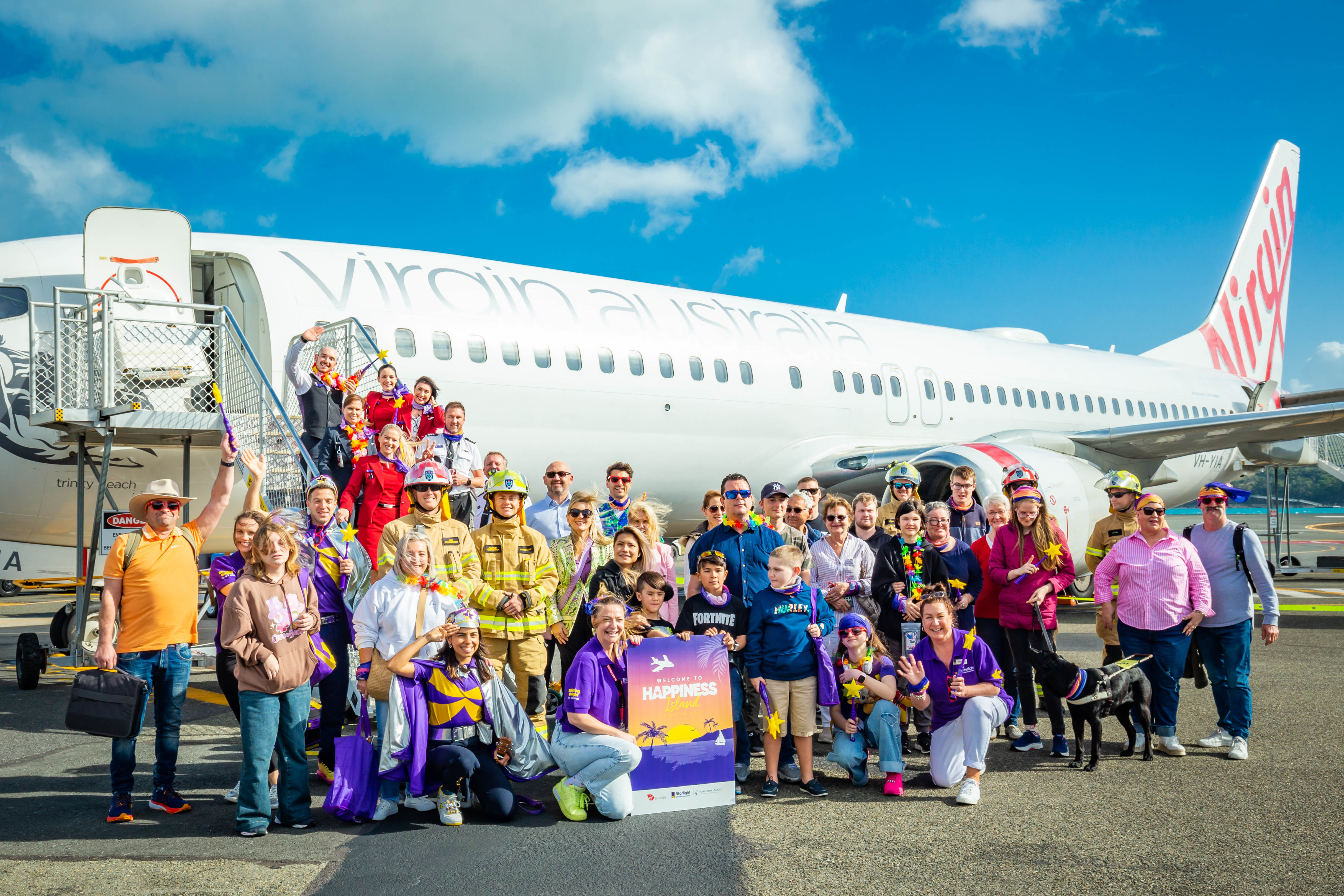 Children and volunteers standing in front of Virgin Australia plane on tarmac celebrating Starlight Childrens Charity.