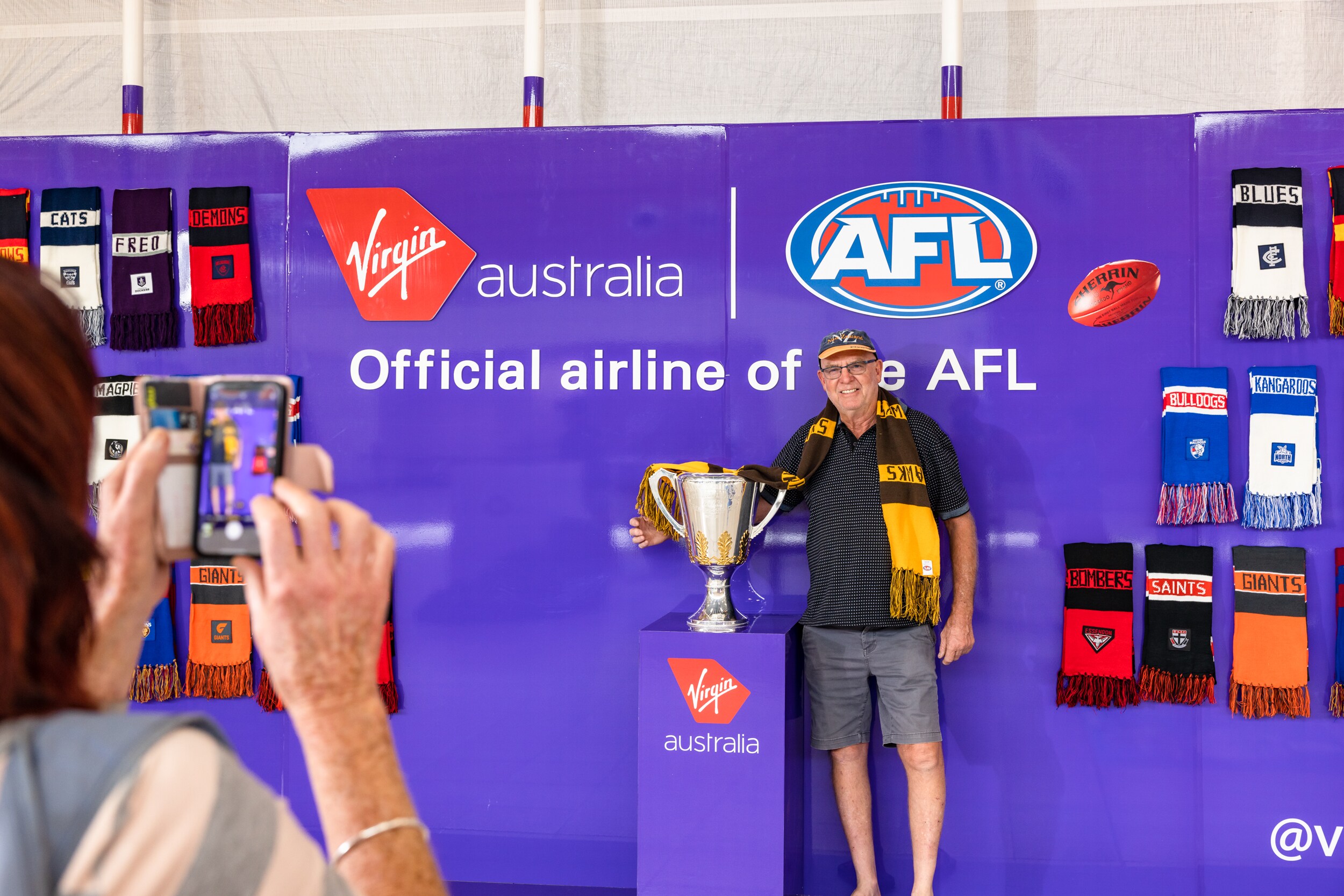 Hawthorn Football Club supporter standing proudly in front of the AFL Grand Final trophy