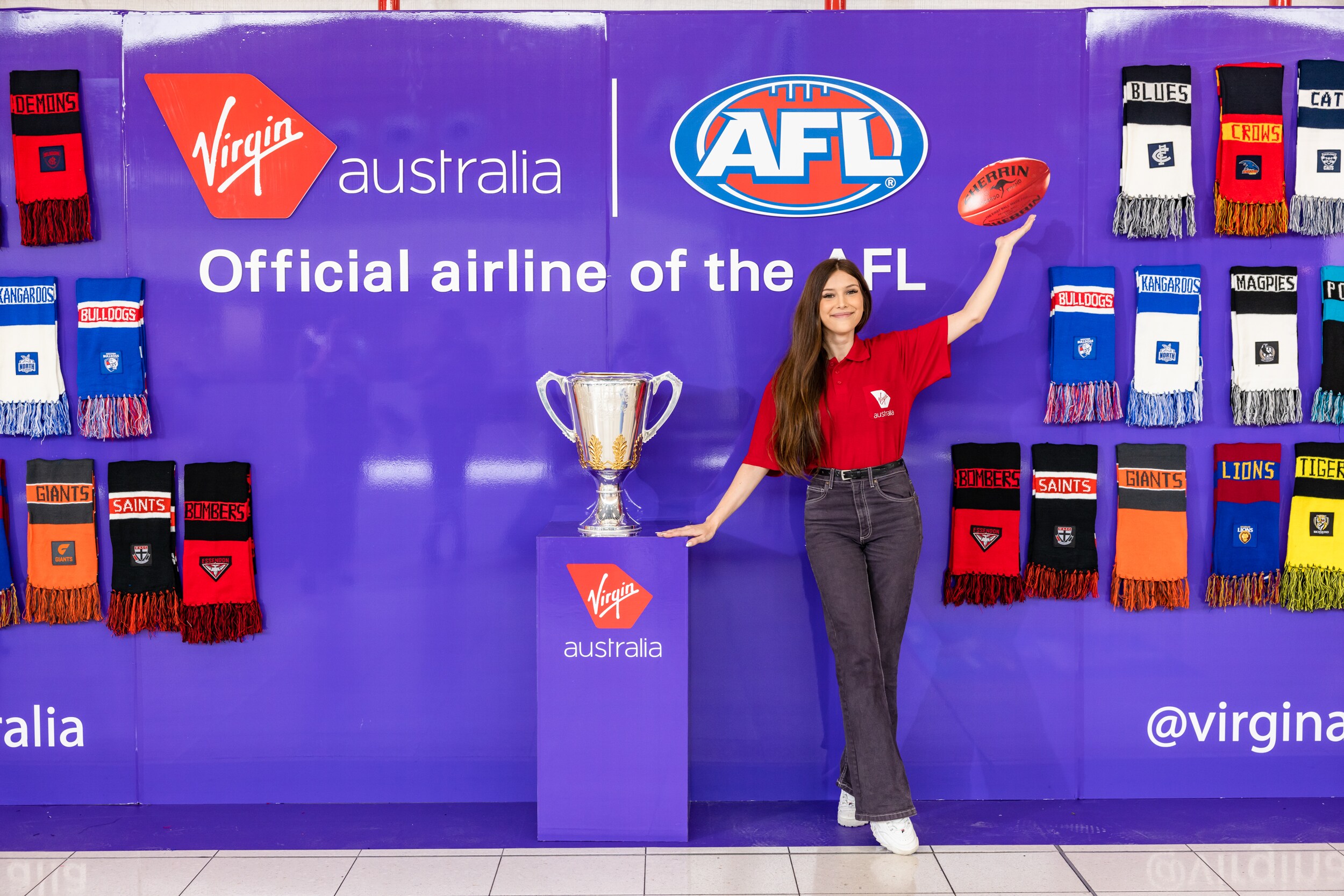 Woman standing in front of AFL scarf merchandise and the AFL Grand Final trophy