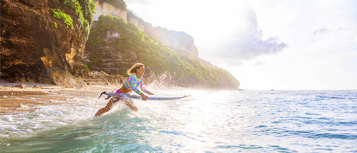 Female surfer getting into the waves in Bali