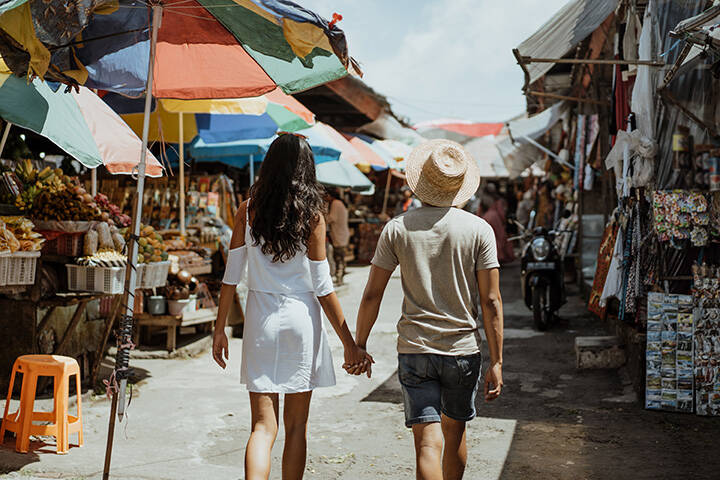 Tourist couple walking in souvenir market in Bali 