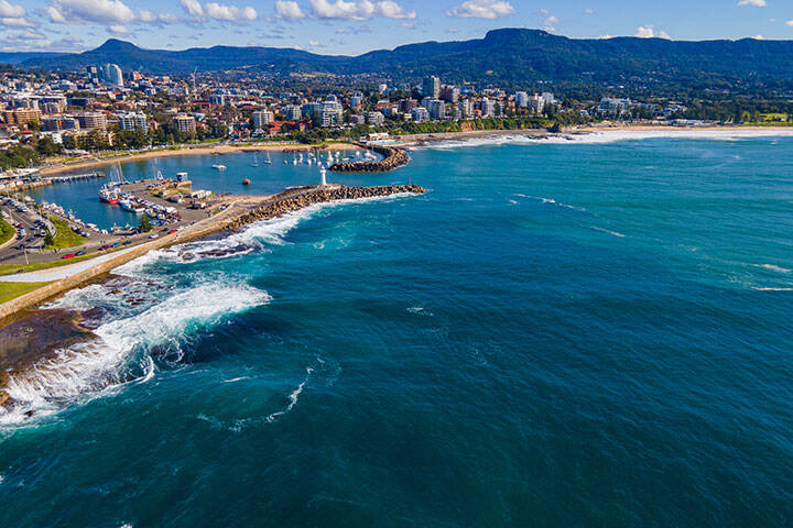 Aerial drone view of Breakwater Lighthouse toward Continental Pool at Wollongong on the New South Wales South Coast, Australia showing the breakwater structure and boat moorings on a sunny day