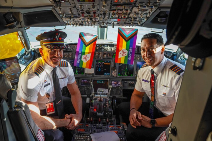 Flight crew sitting in cockpit with pride flag ready for Virgin Australia Pride Flight