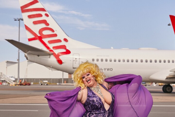 Drag queen posing in front of plane before Virgin Australia Pride Flight